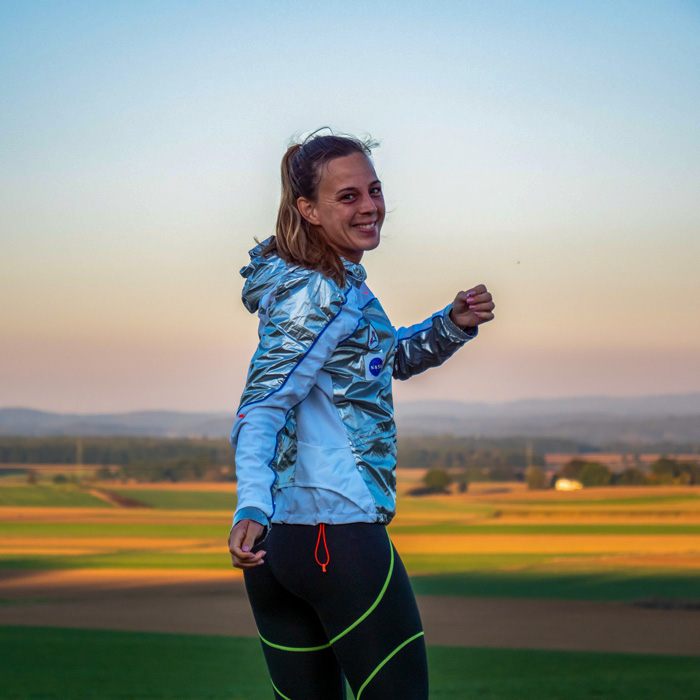 Frau mit Sportkleidung steht auf einem Feld und lächelt Frau mit Sportkleidung steht auf einem Feld und lächelt