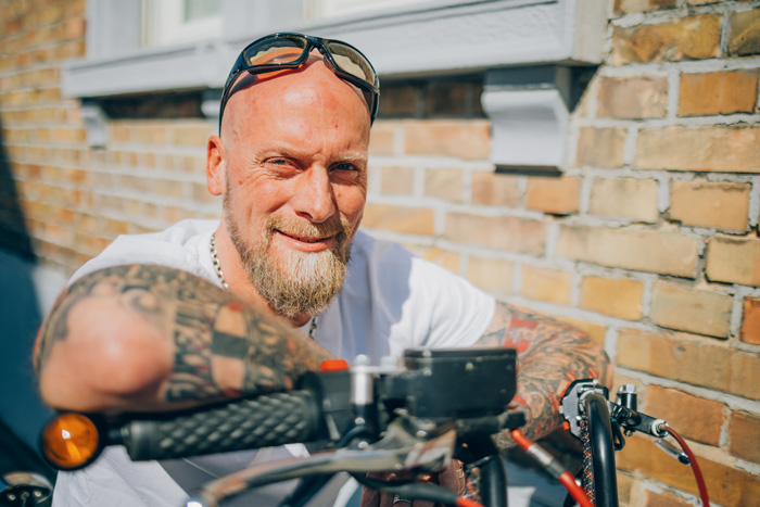 Mann mit tätowierten Armen sitzt auf Motorrad Mann mit tätowierten Armen sitzt auf Motorrad