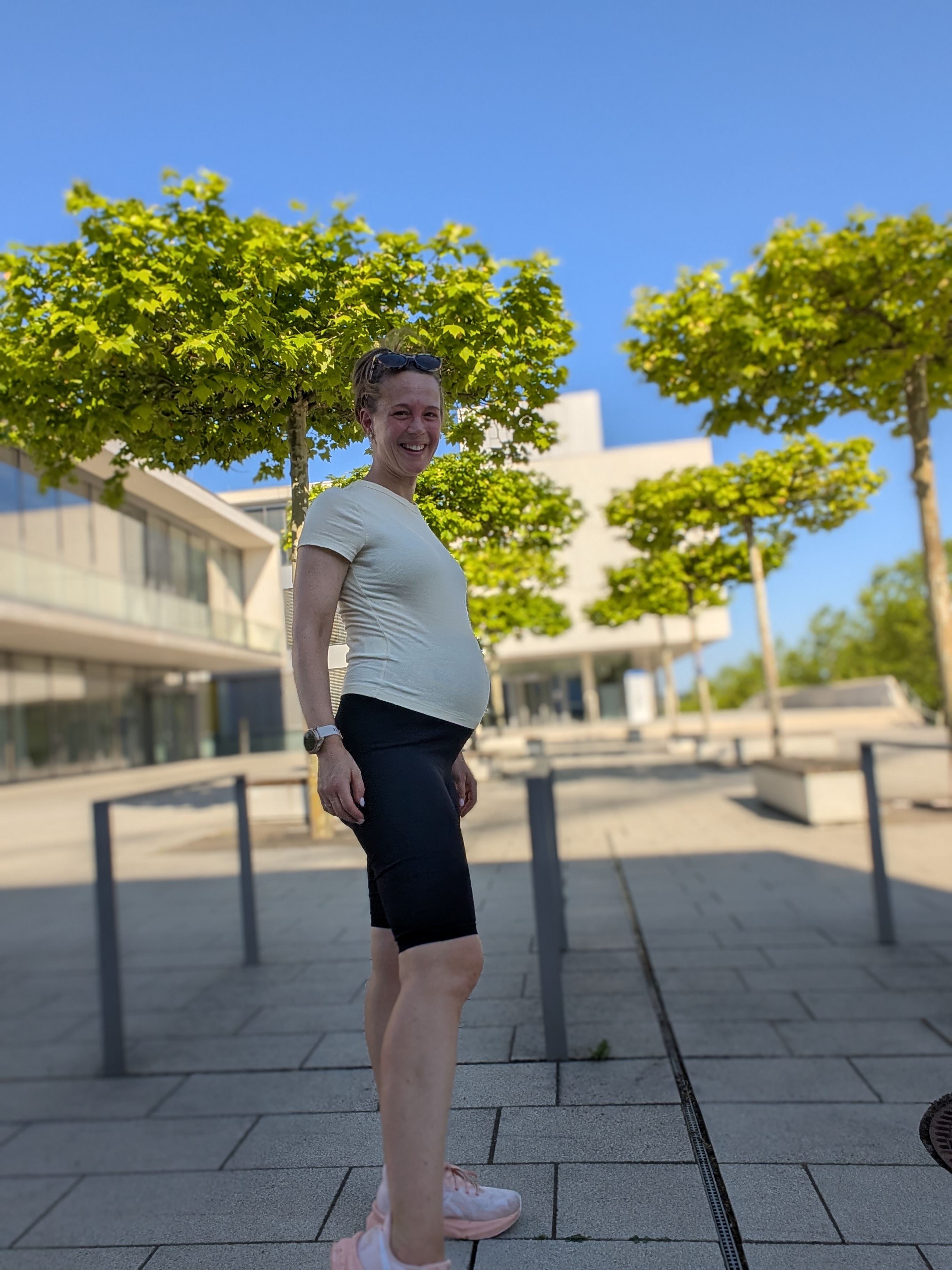 Schwangere Frau lacht in die Kamera.