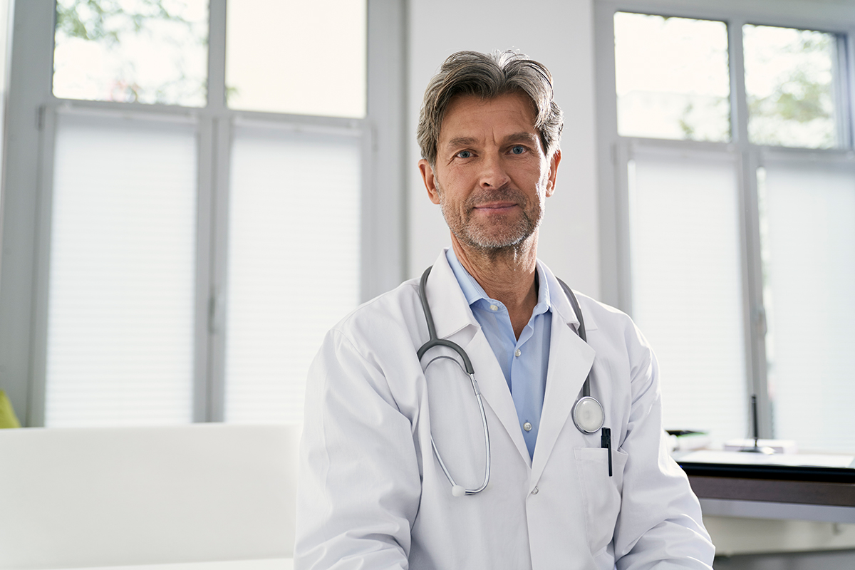 Neurodermitis Arzt sitzt vor Fensterfront Neurodermitis Arzt sitzt vor Fensterfront