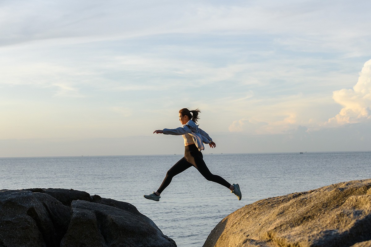 Frau springt über die Lücke zweier Steine als Symbolik für mehr Lebensqualität bei  Neurodermitis
