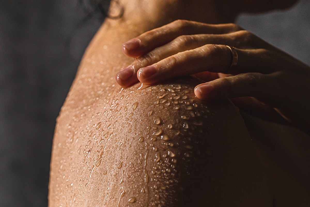 Frau mit Wasserperlen auf der Schulter beim Duschen