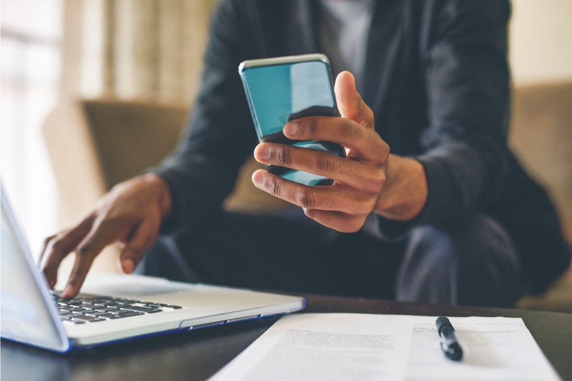 Mann arbeitet am Laptop und am Smartphone